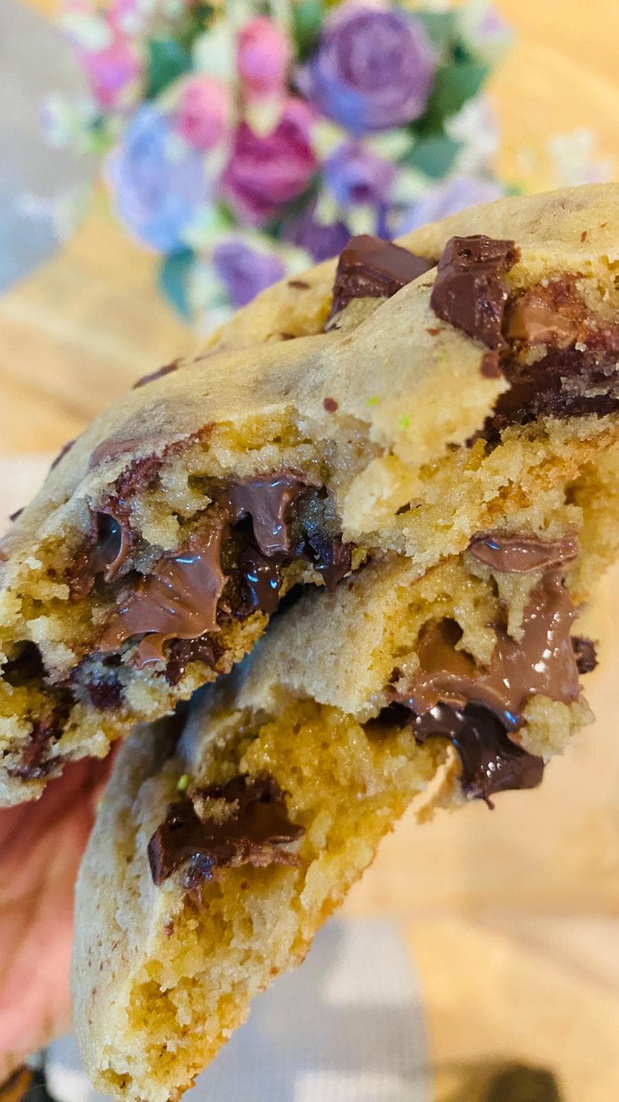 Chocolate chip cookie torn open with molten chocolate stretching