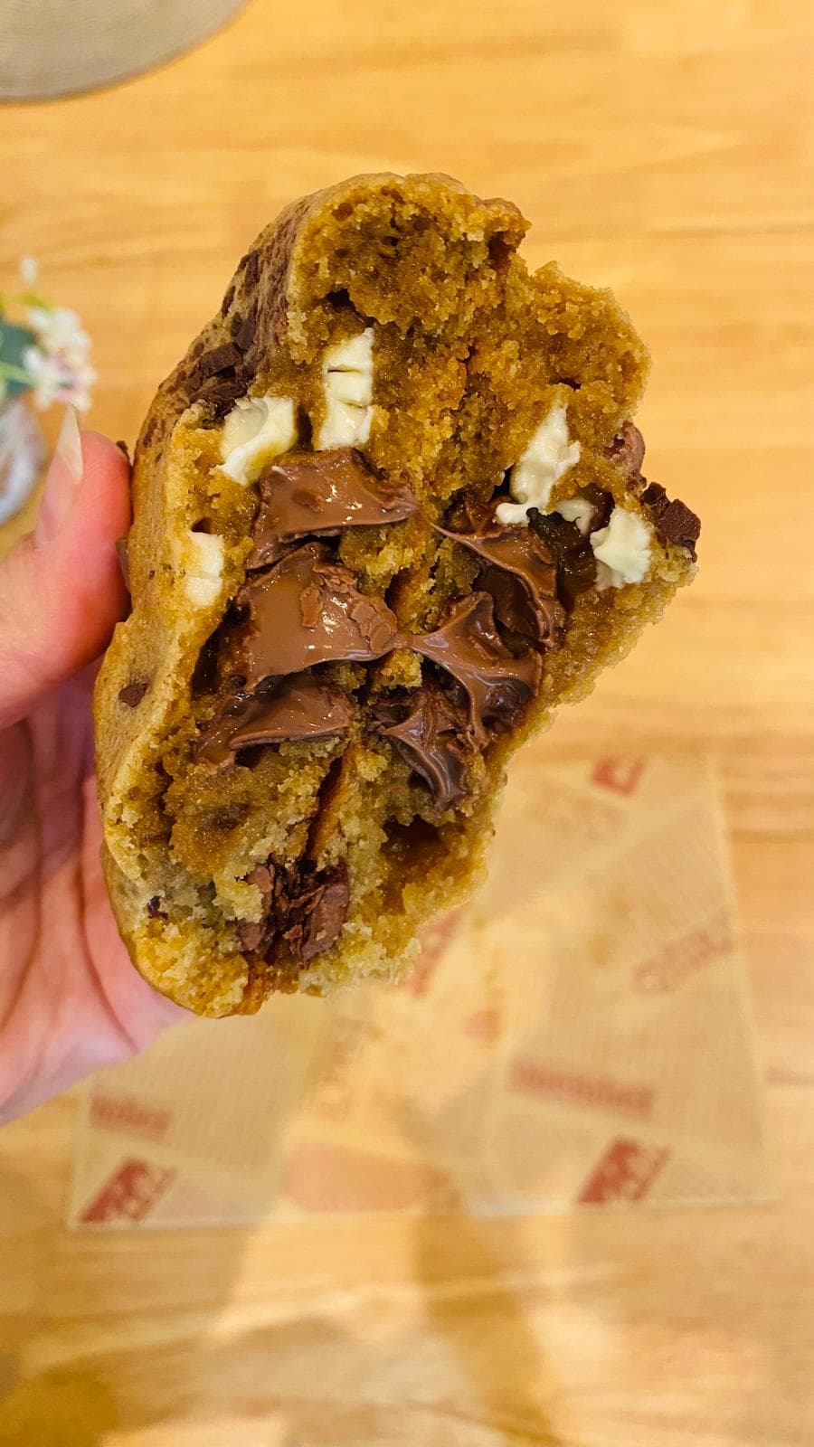 Chocolate chip cookie torn open with molten chocolate stretching — alternate view
