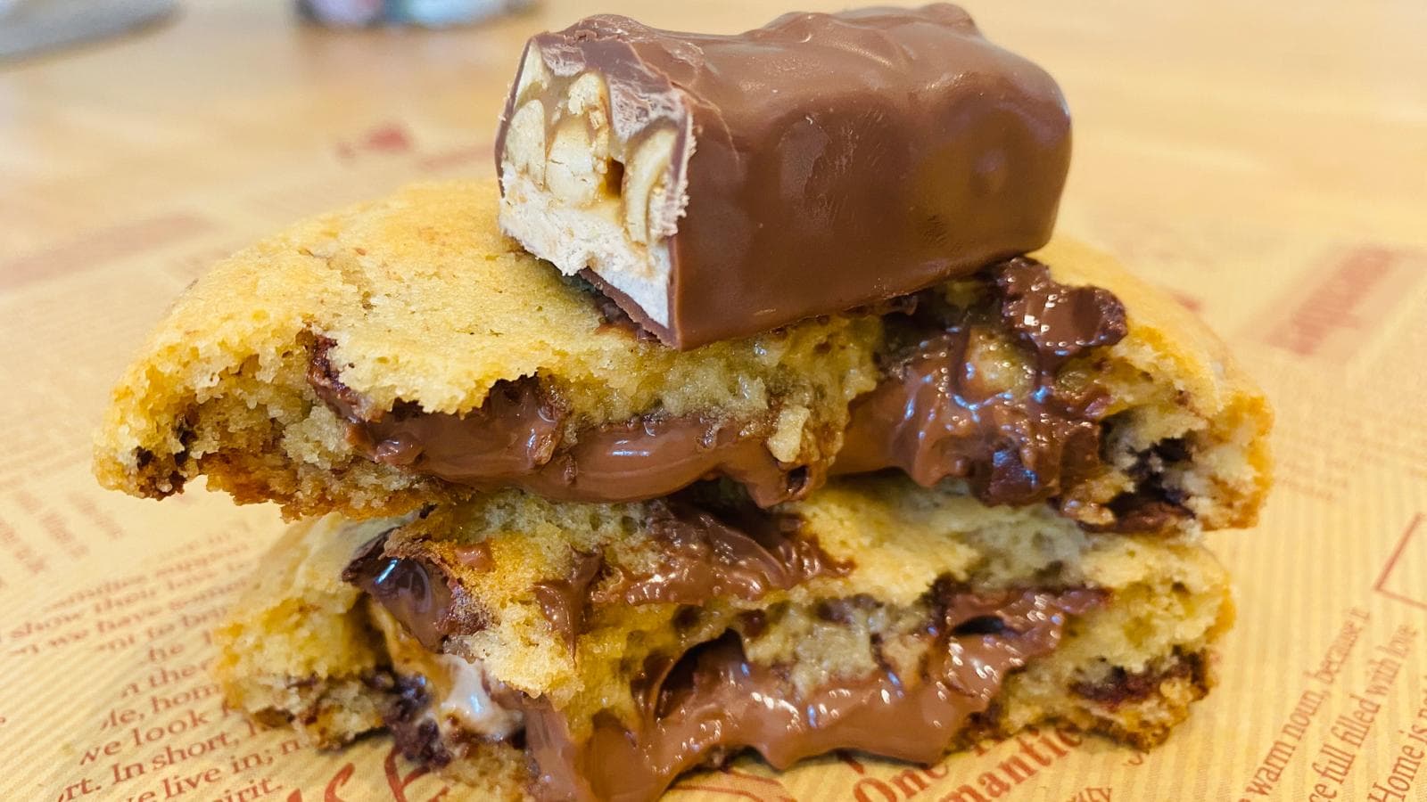 Snickers cookie torn open with molten caramel, nougat and peanut stretching